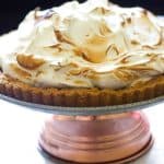 Salted Chocolate S'mores Tart with Toasted Marshmallows sitting on a cake platter