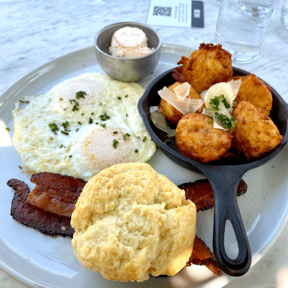 plate of breakfast including eggs, homemade tater tots, bacon and biscuits from Magnolia Table.