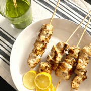 plate of grilled lemon chicken with a cup of basil vinaigrette