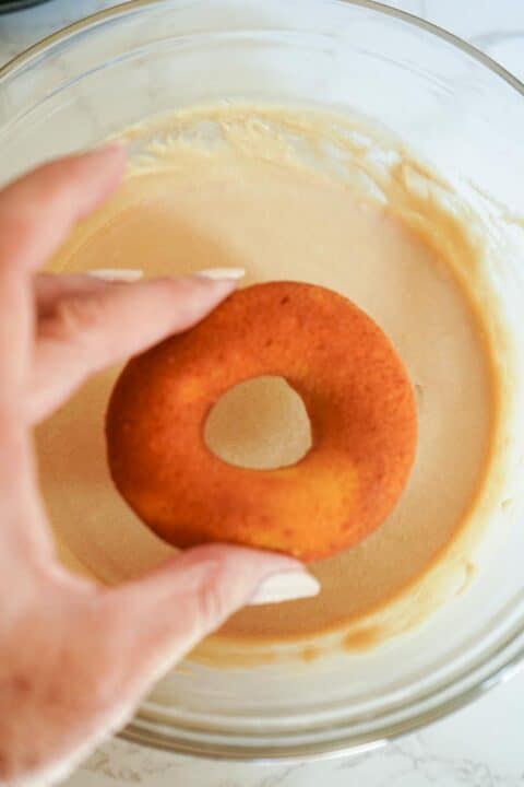 picture of a hand dipping a pumpkin spice latte donut