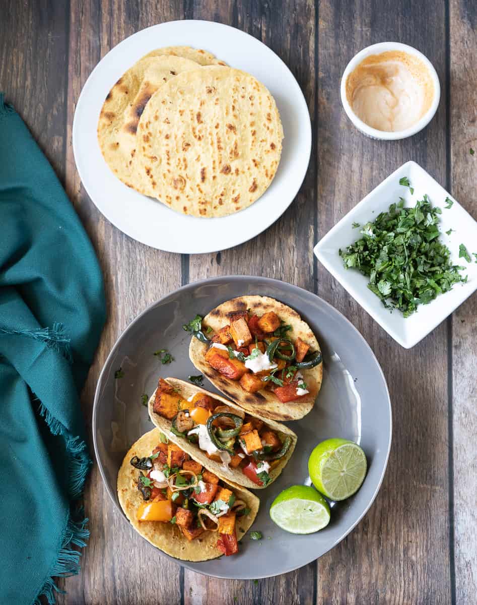 Plate of sweet potato tacos, tortillas and cilantro