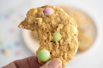 Hand holding a cookie with a bite out of it.