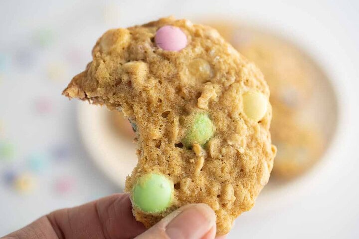 Hand holding a cookie with a bite out of it.