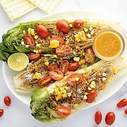White plate with grilled romaine salad with spicy caesar vinaigrette.