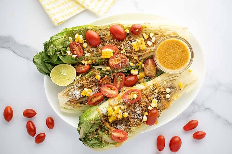 White plate with grilled romaine salad with spicy caesar vinaigrette.